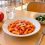 Pasta al pomodoro, verdure cotte, pane, mela e acqua su un tavolo di mensa scolastica